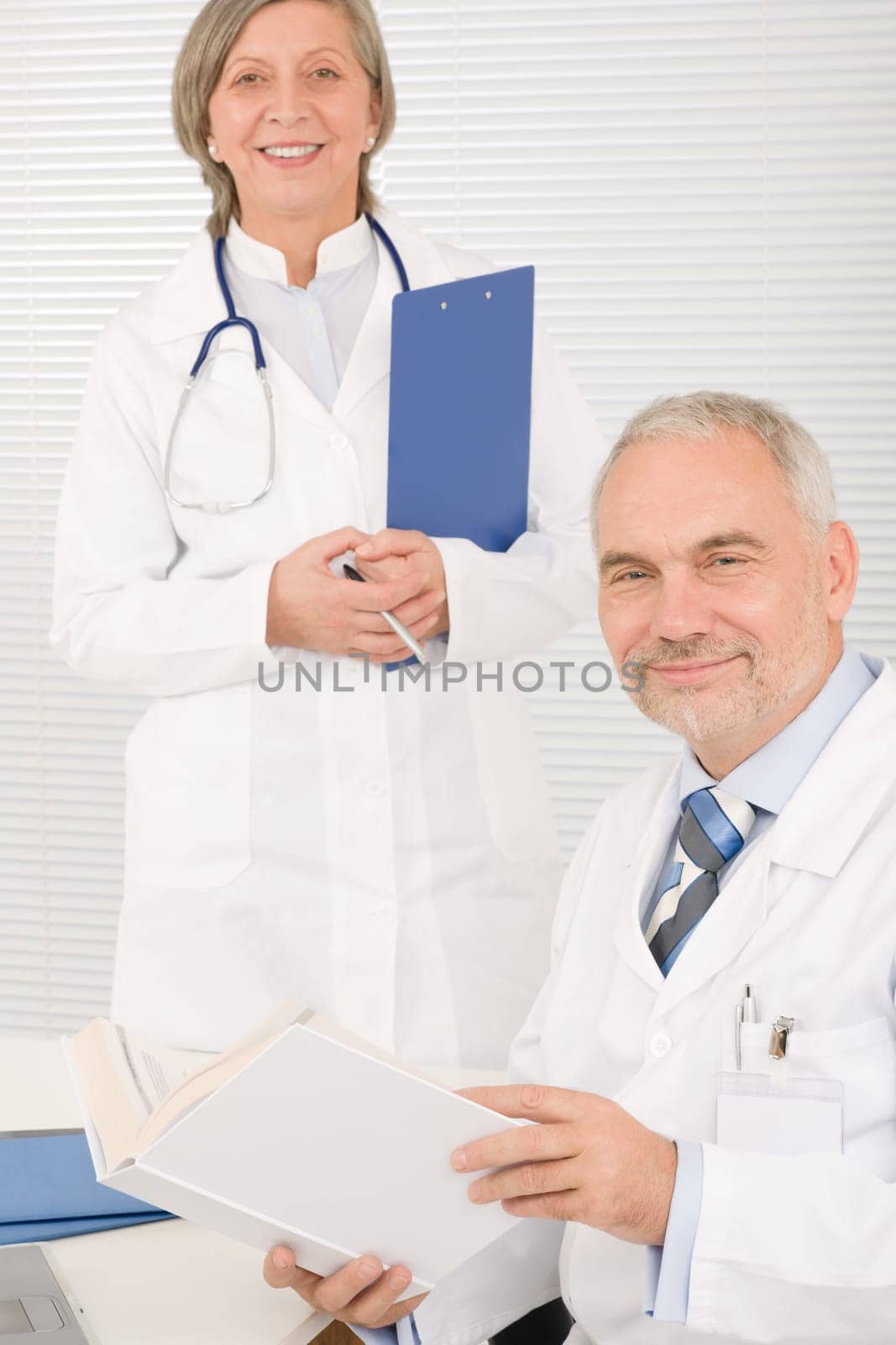 Medical senior doctor male reading book with professional female colleague