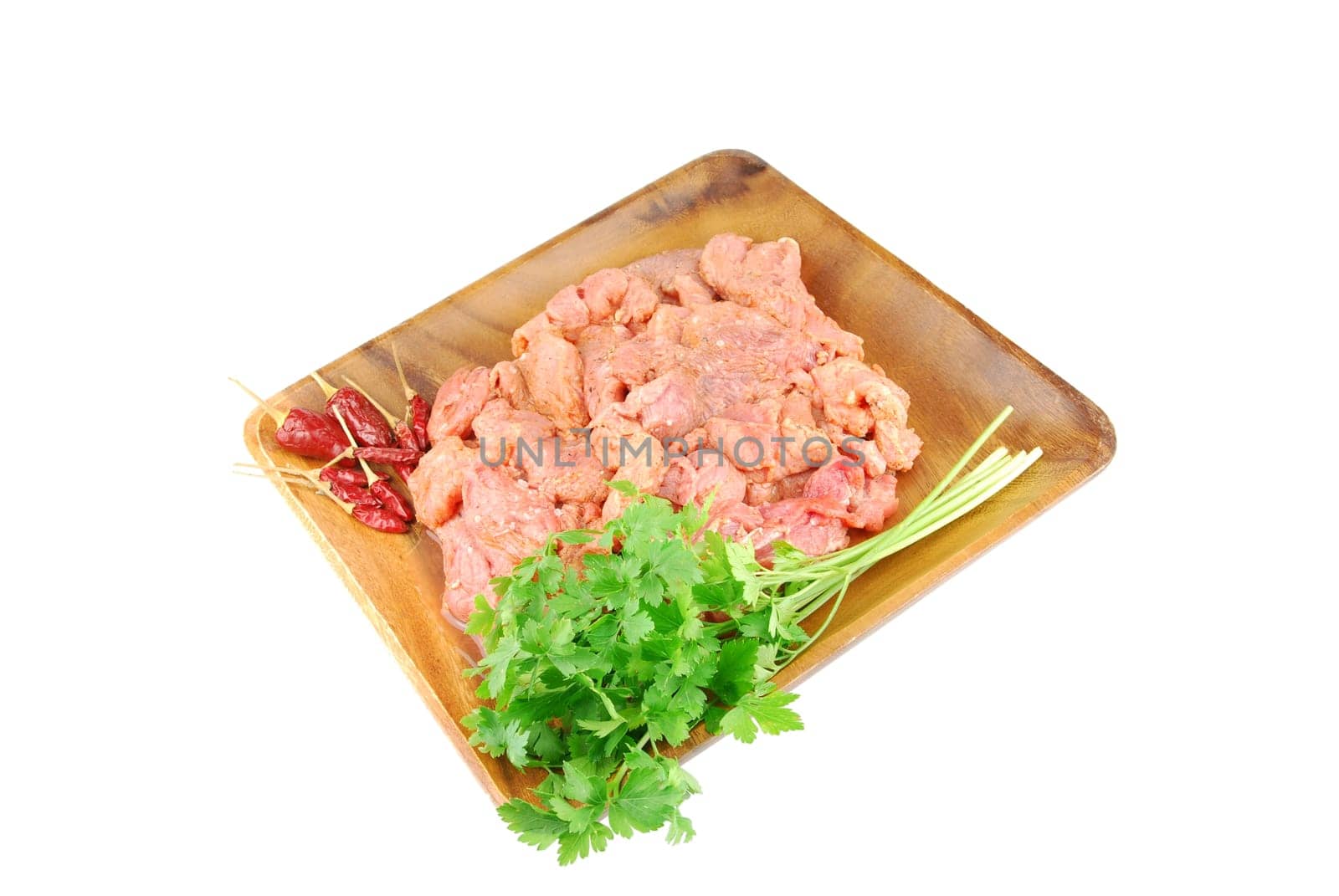 raw pork meat with red pepper and parsley ready to be cooked on a wooden tray (over white)