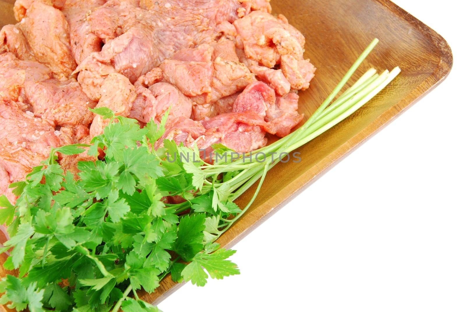 raw pork meat with parsley ready to be cooked on a wooden tray (over white)