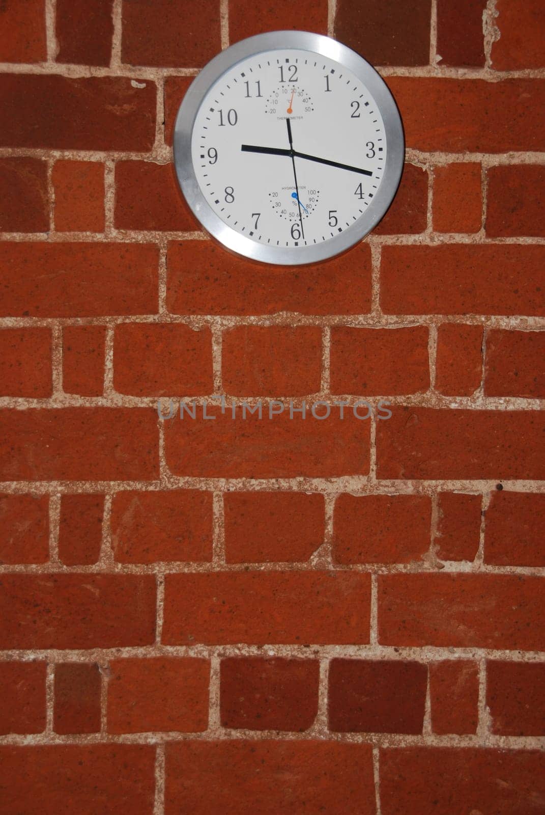 grey and white wall clock on a residential brick flat