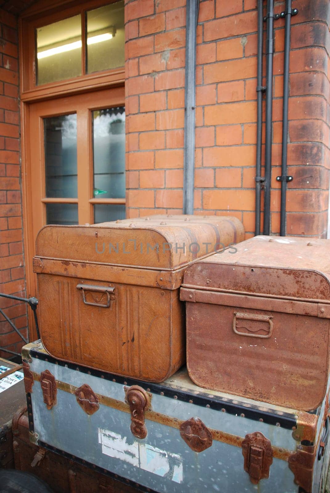 heap of vintage old suitcases in front of a brick wall building