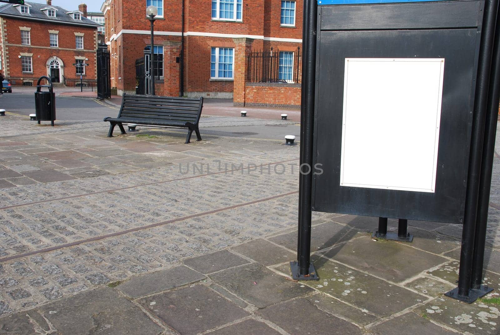empty billboard at the sidewalk with wooden bench and typical british brick wall buildings