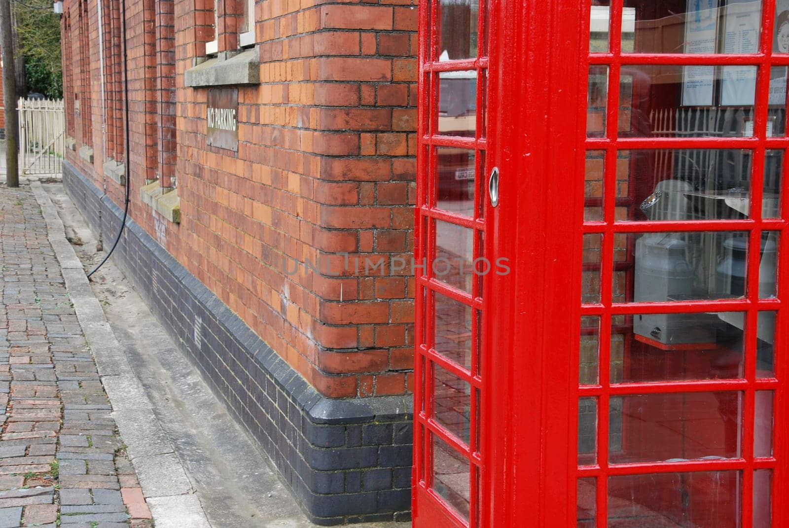 typical red telephone booth and brick wall building on the background
