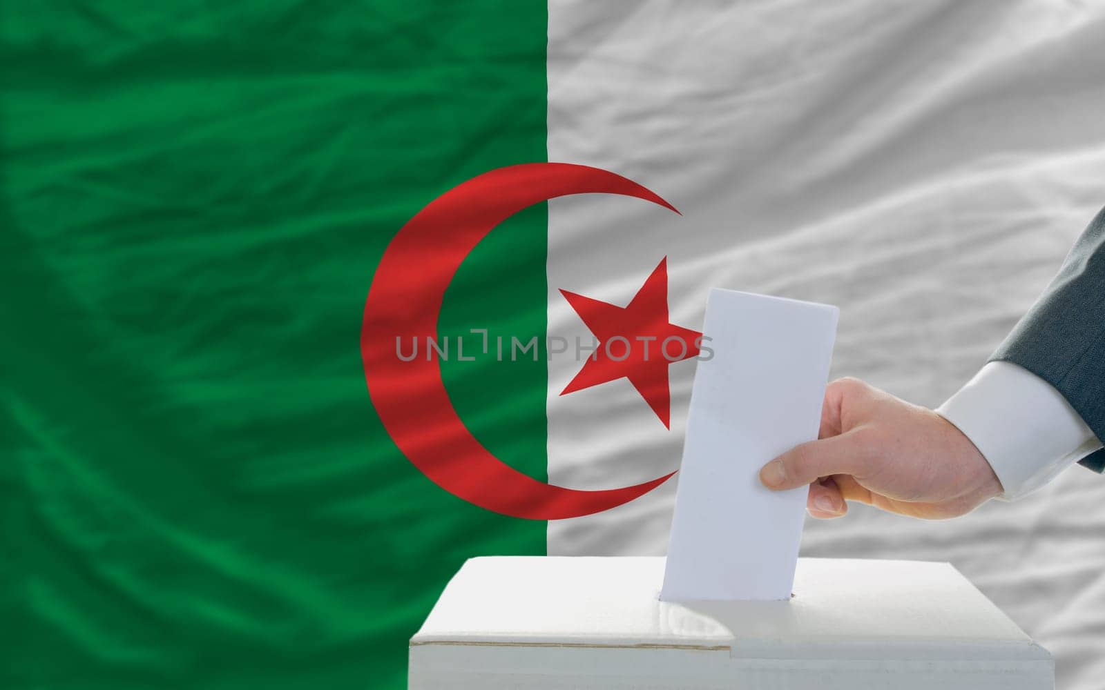 man putting ballot in a box during elections in algeria