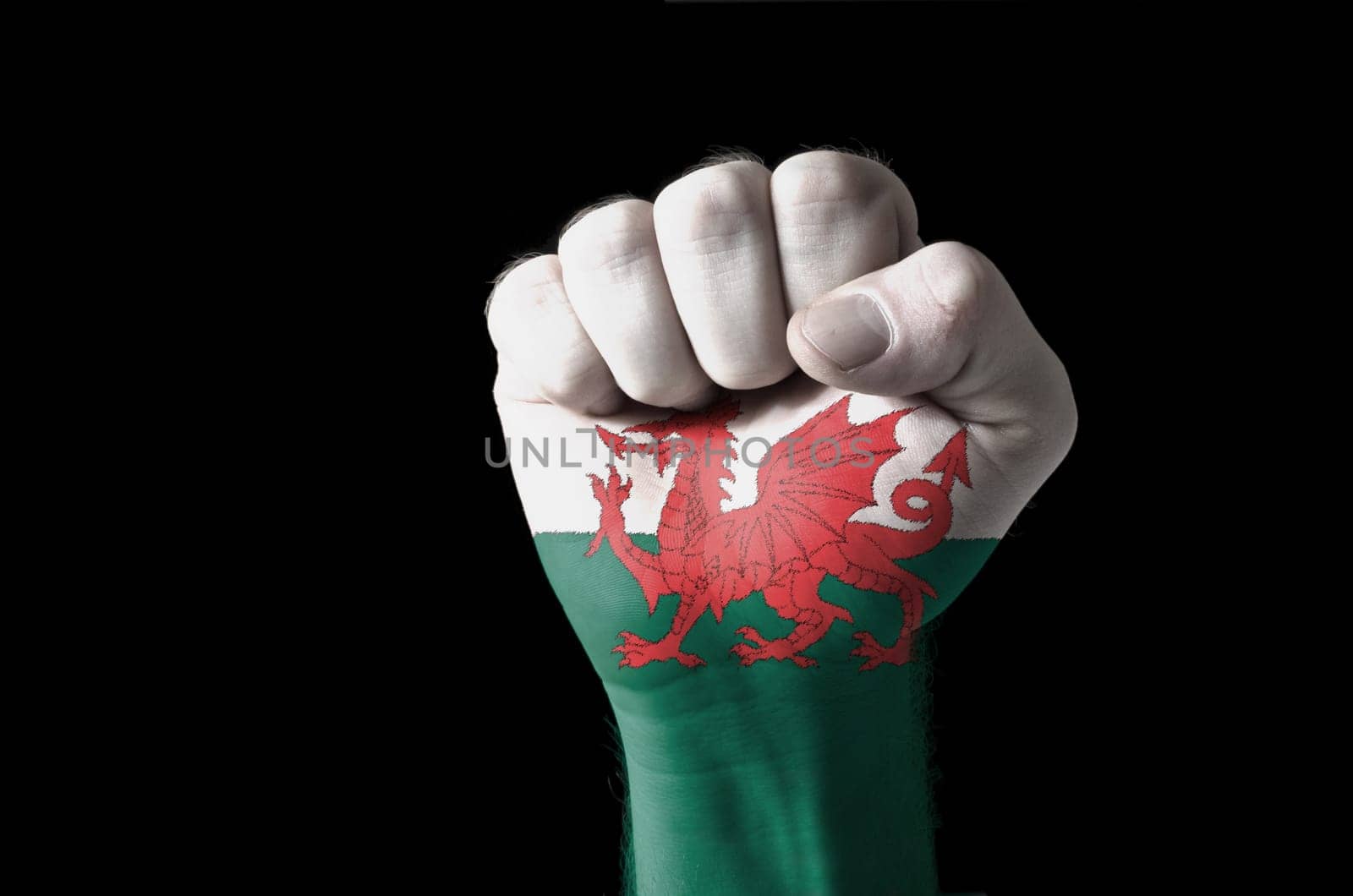 Low key picture of a fist painted in colors of wales flag