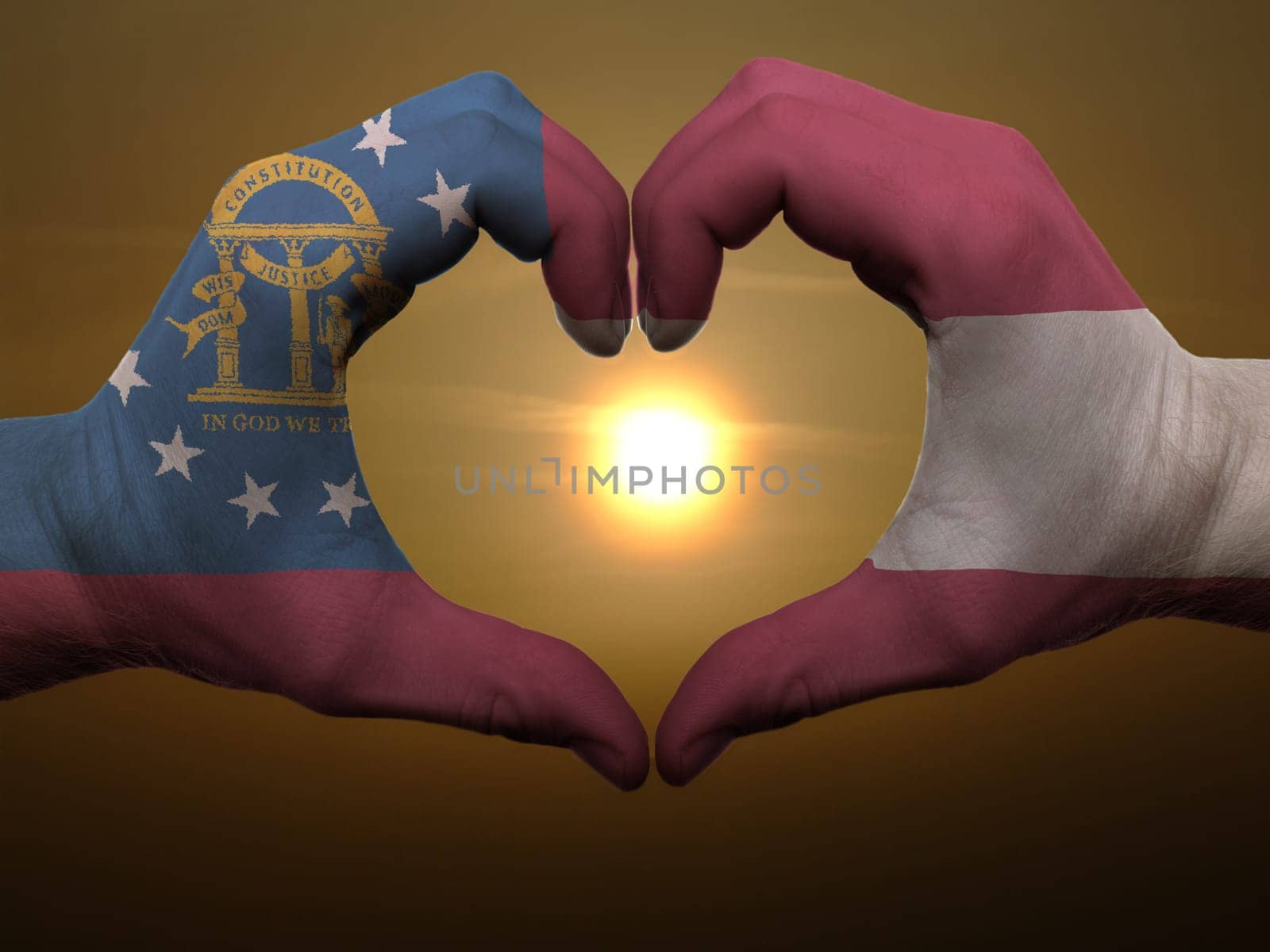 Gesture made by georgia flag colored hands showing symbol of heart and love during sunrise