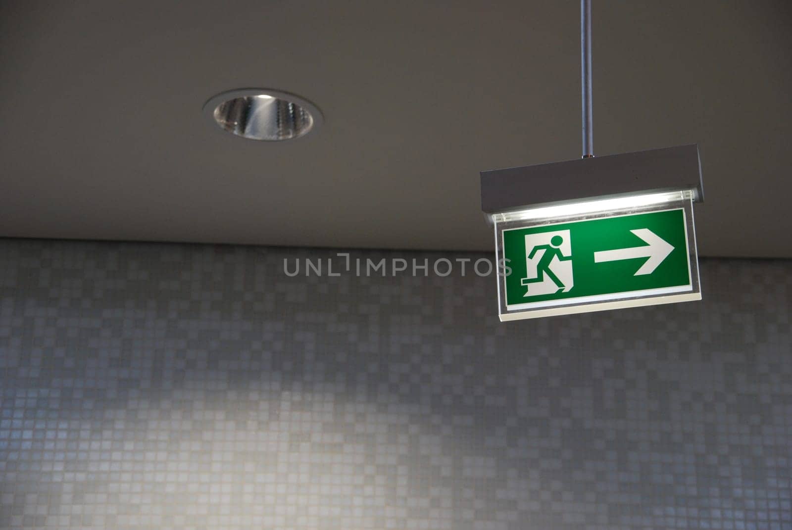 beautiful green emergency exit sign hanging on a ceiling
