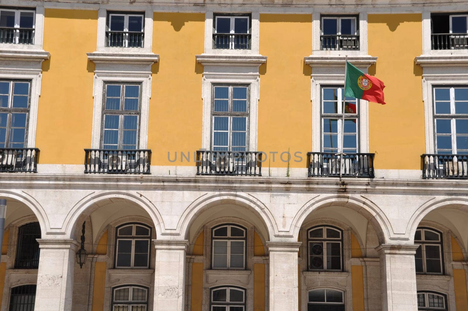 yellow building with portuguese flag surrounding Commerce Square in Lisbon, Portugal