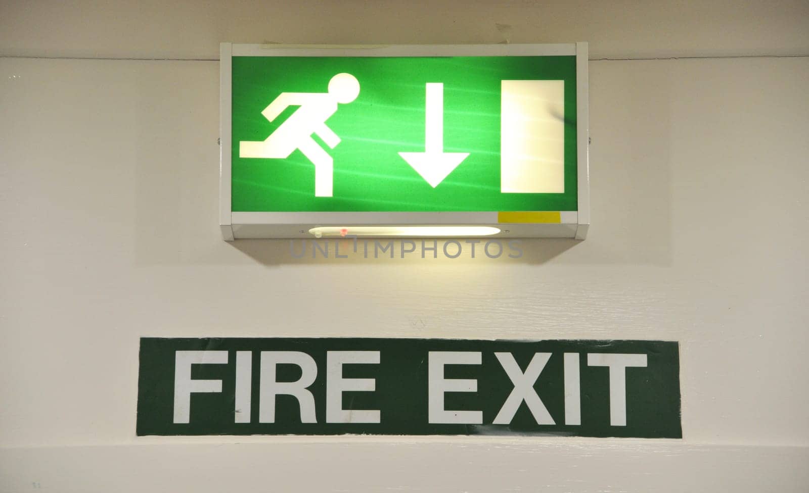 green and white warning sign glowing regarding fire exit emergency