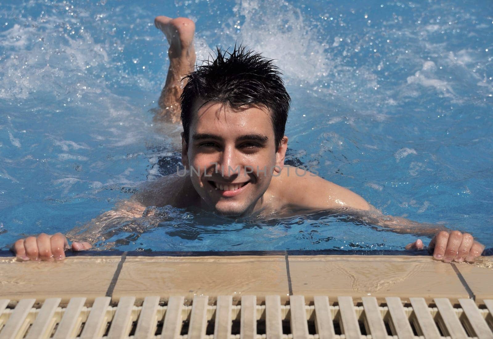 smiling young man doing water gymnastics (front view)