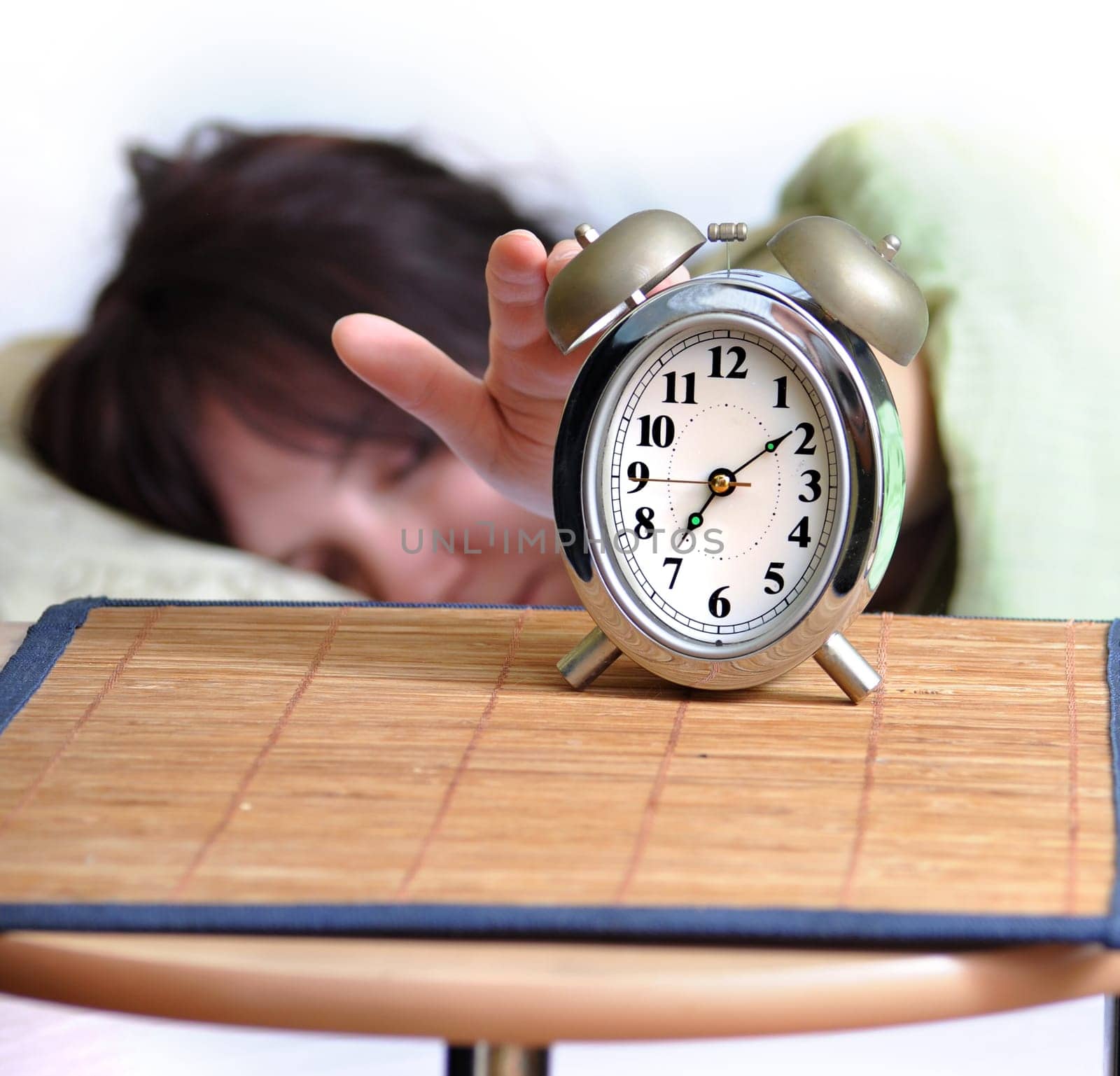 A woman is sleeping with an alarm clock in front and space for your text.