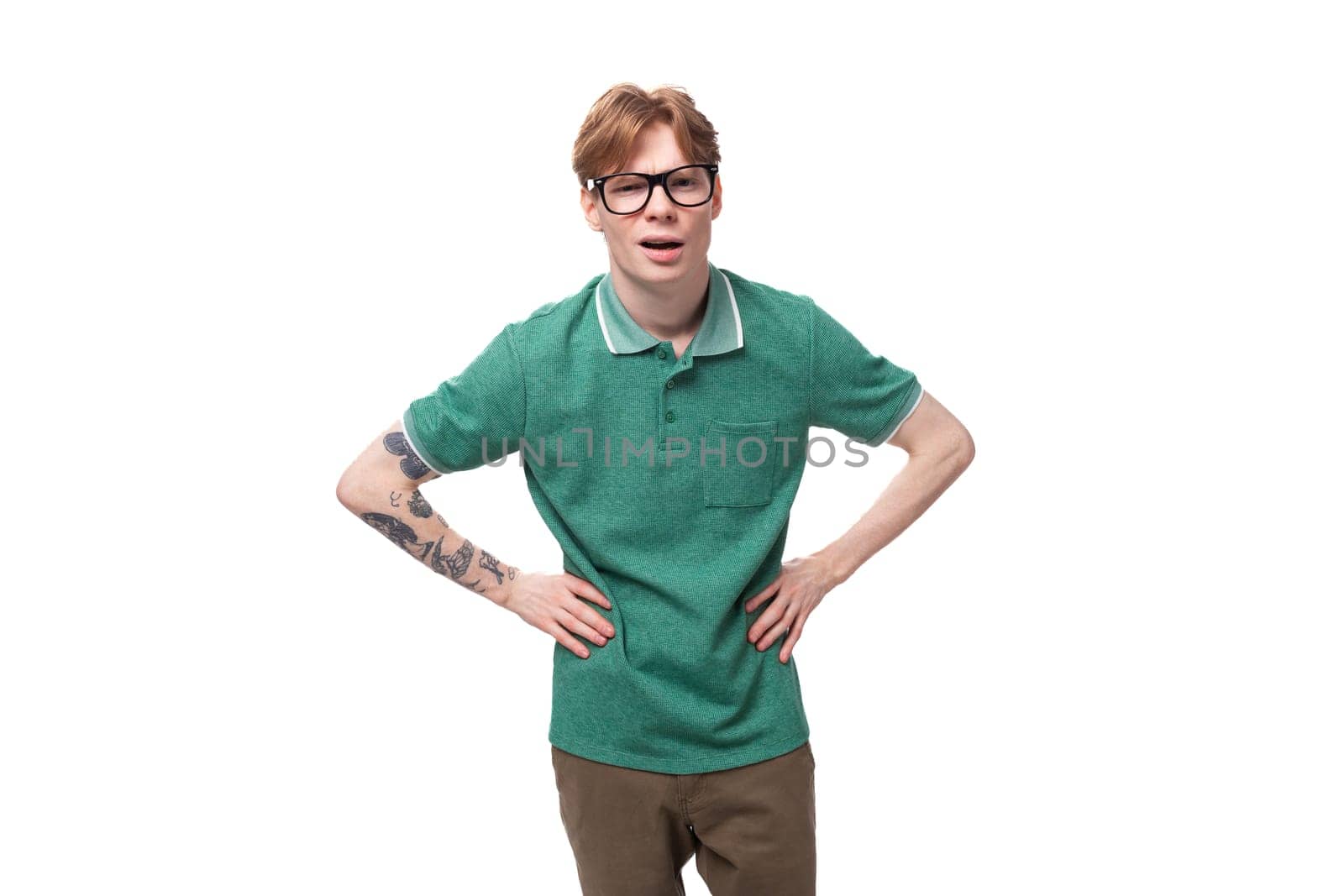 young surprised man with red hair in a green t-shirt on a white background with copy space.