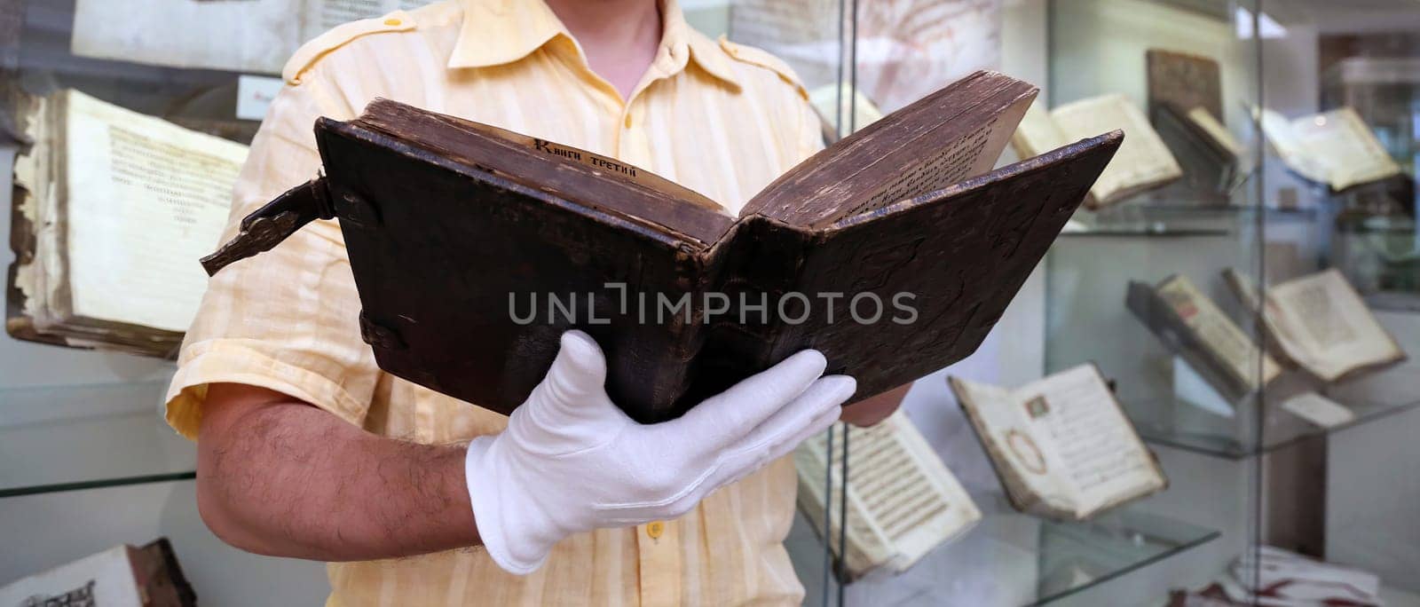 An old book in a scientist's hands, close-up. Christian antique book in the hands of a librarian.