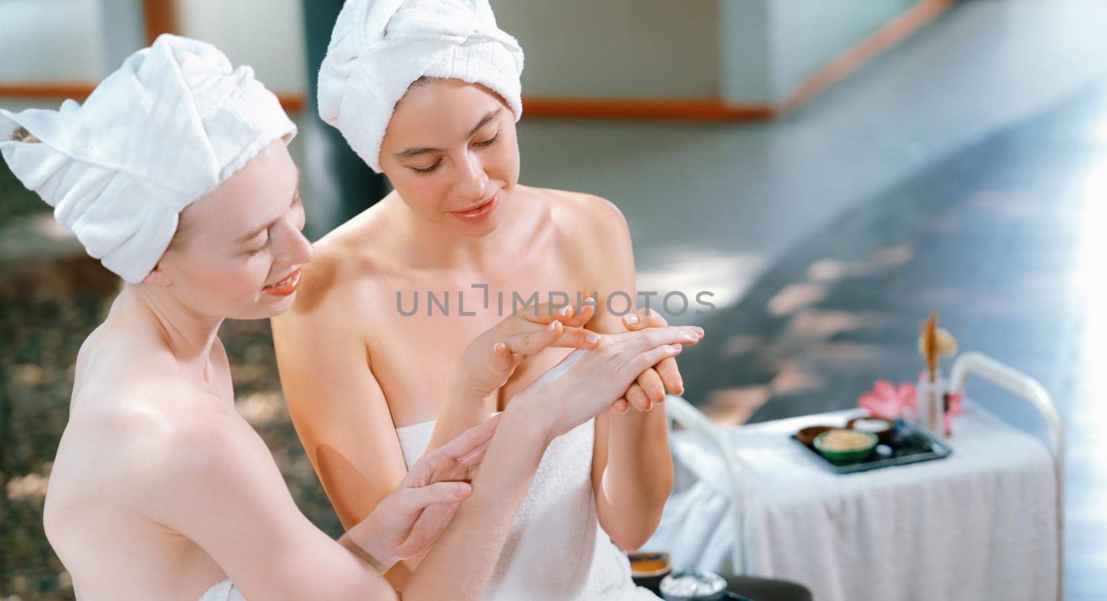 A portrait of two beautiful caucasian woman in white towel using homemade facial mask rounded by peaceful natural environment at outdoor. Healthy and beauty concept. Blurring background. Tranquility.