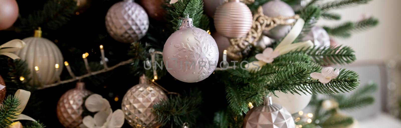 Festive Christmas background, card. Gold Christmas garland, pink Christmas tree decorations and white artificial fir tree on a pink background.