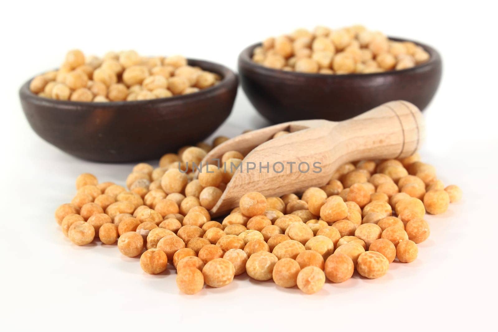 yellow peas and a shovel against white background