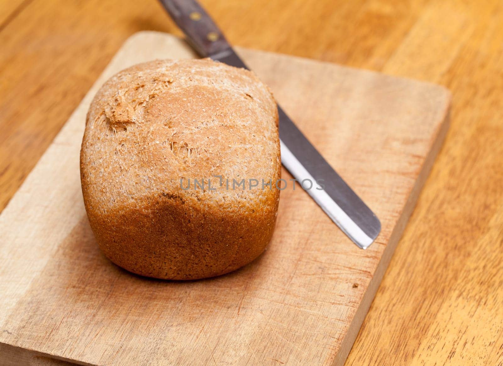 Whole wheat loaf from a bread making machine ready to cut on cutting board