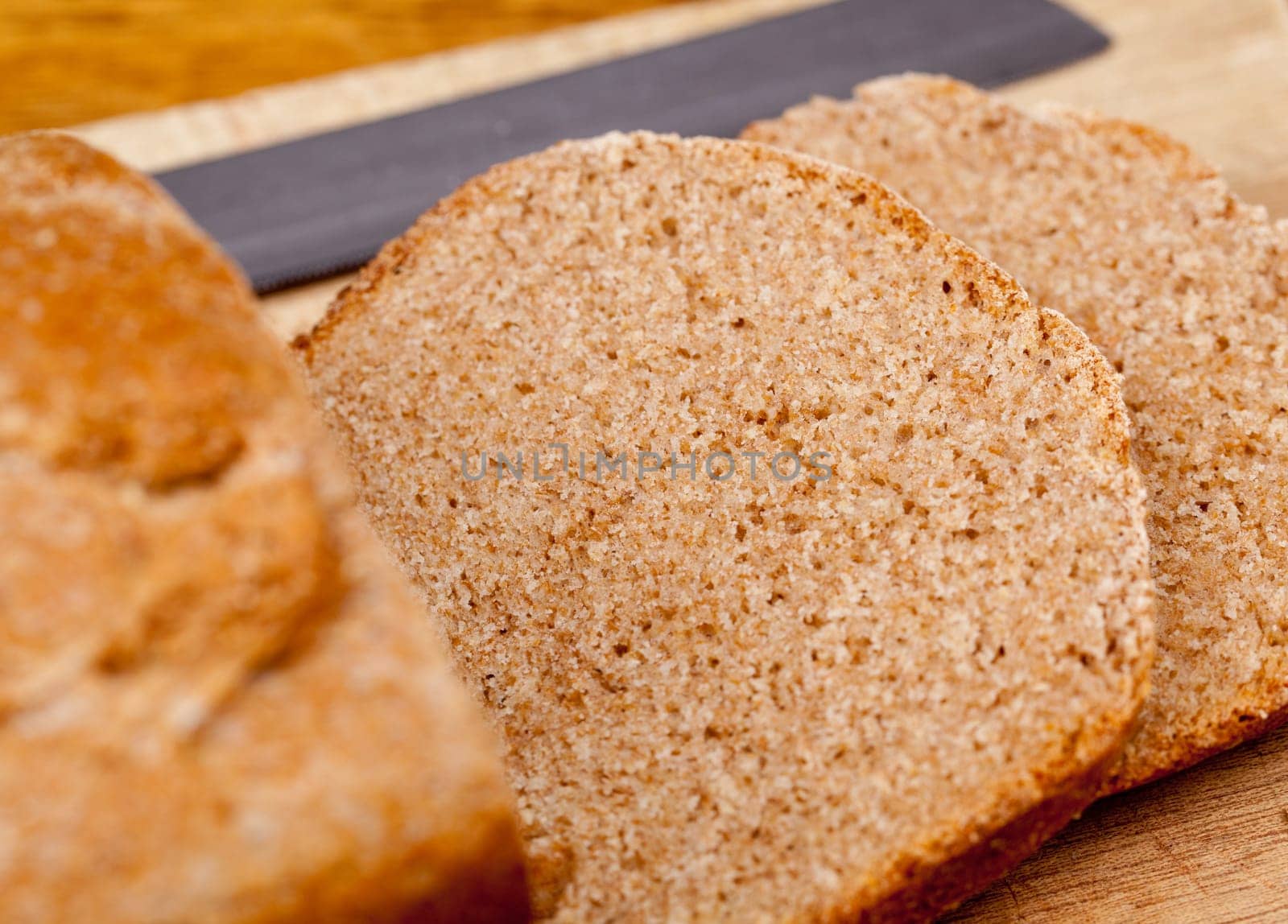 Slices of home made wheat bread on breadboard with knife