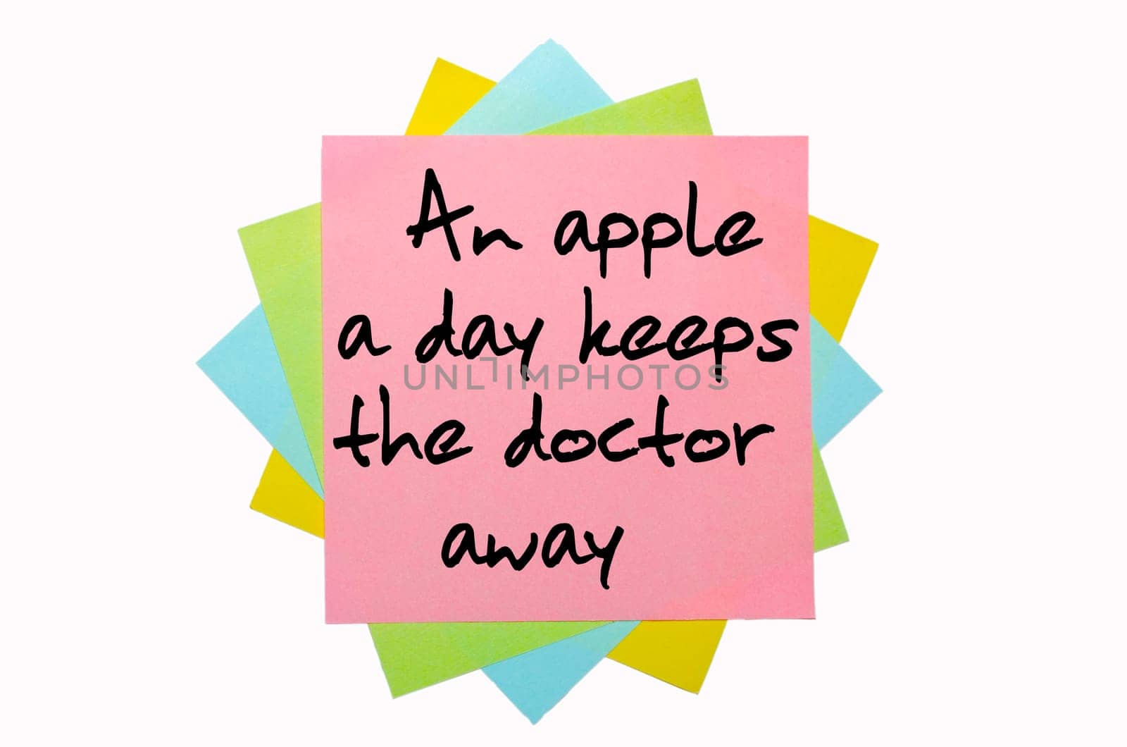 text "An apple a day keeps the doctor away"" written by hand font on bunch of colored sticky notes"