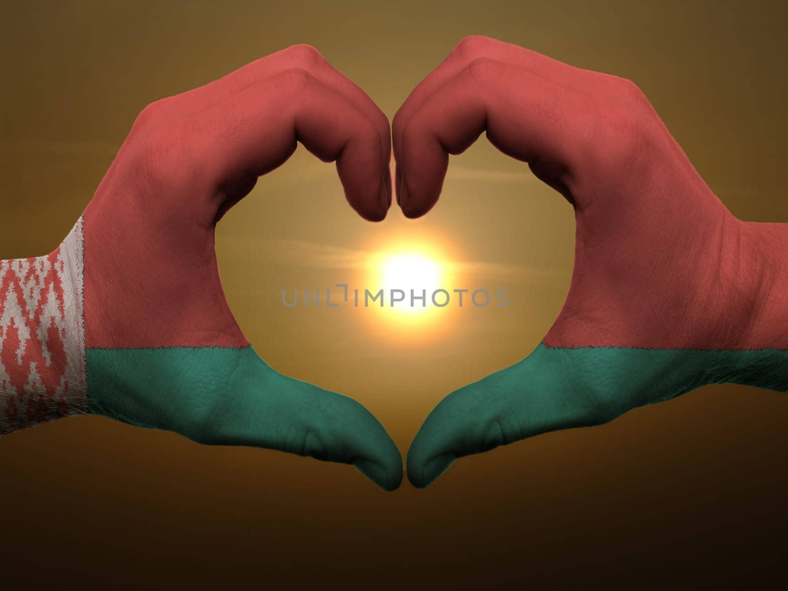 Gesture made by belarus flag colored hands showing symbol of heart and love during sunrise