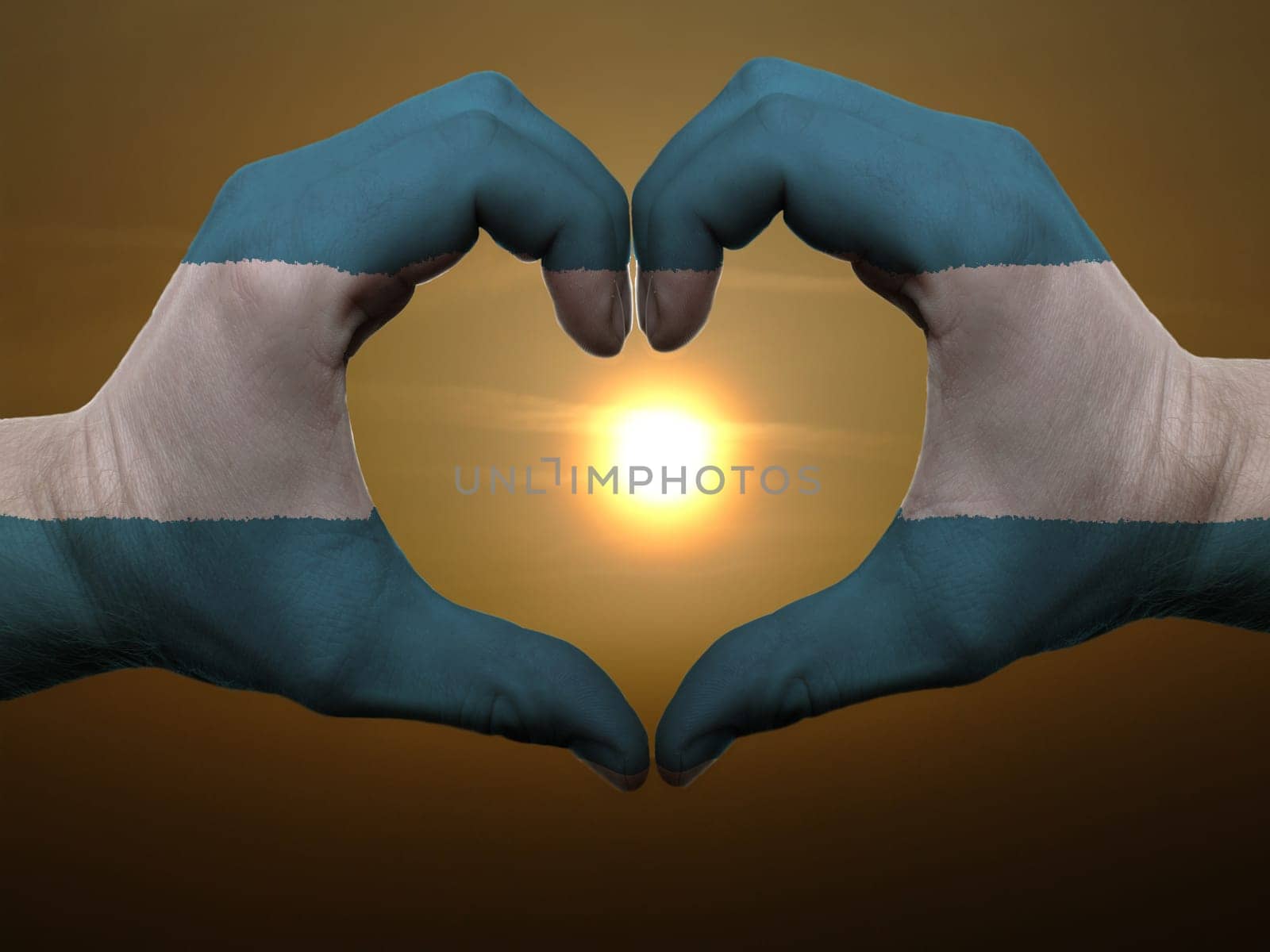 Gesture made by el salvador flag colored hands showing symbol of heart and love during sunrise
