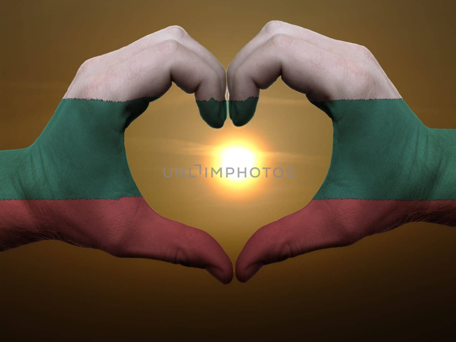 Gesture made by bulgaria flag colored hands showing symbol of heart and love during sunrise