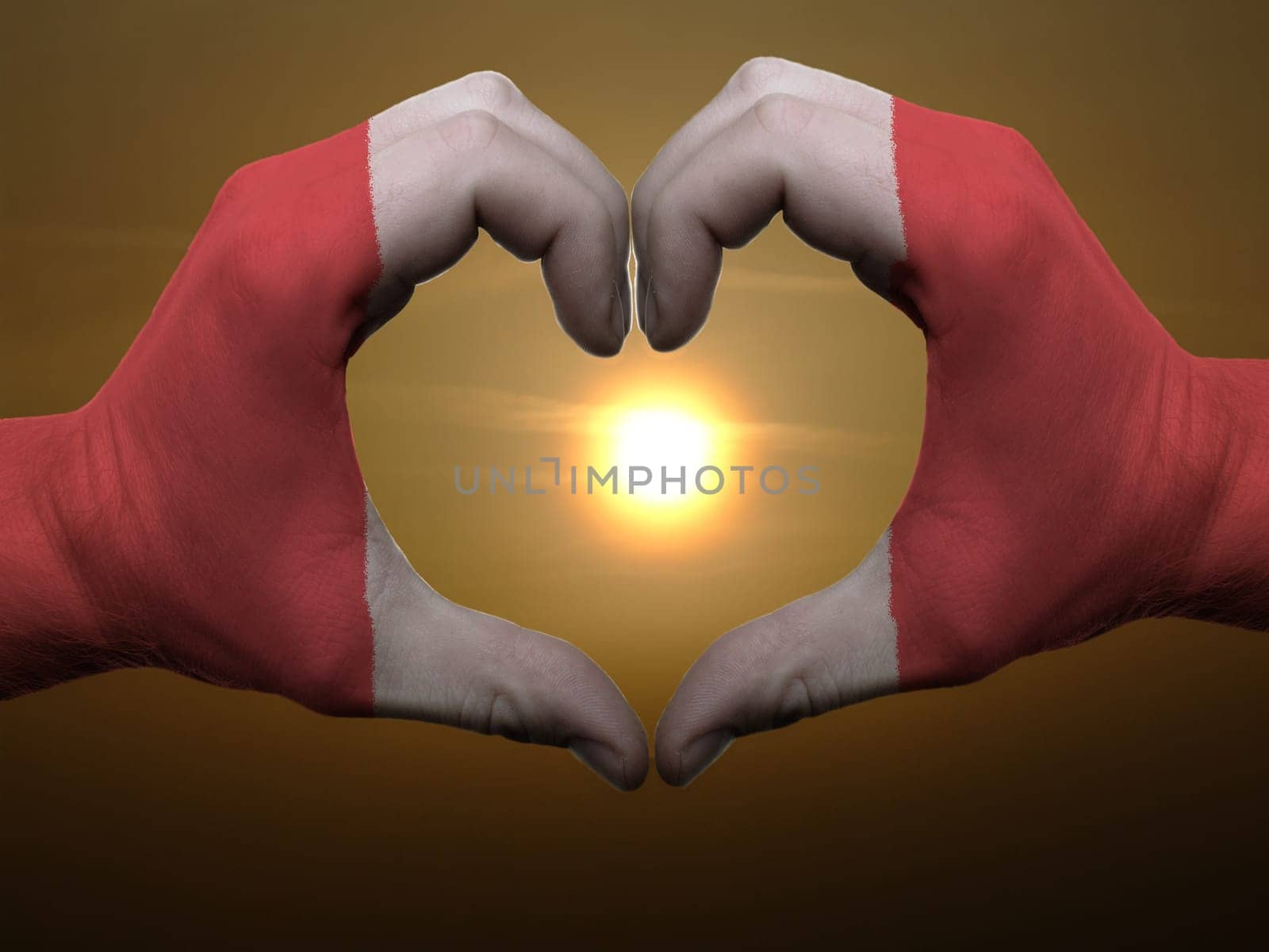 Gesture made by peru flag colored hands showing symbol of heart and love during sunrise