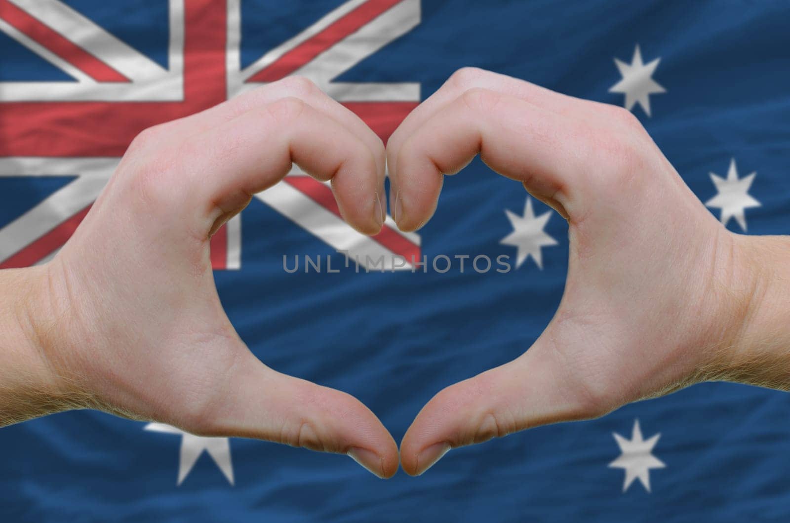 Gesture made by hands showing symbol of heart and love over australian flag