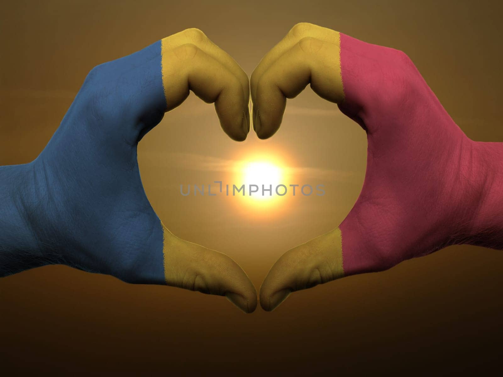Gesture made by romania flag colored hands showing symbol of heart and love during sunrise