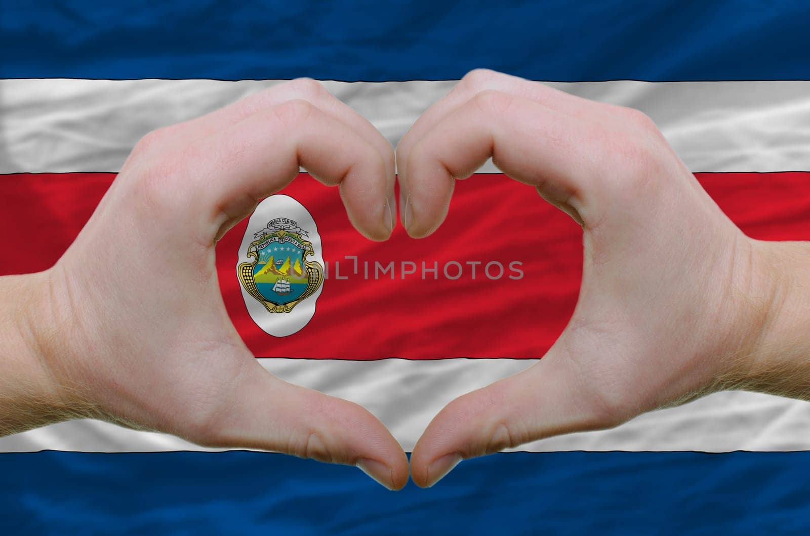 Gesture made by hands showing symbol of heart and love over costarica flag