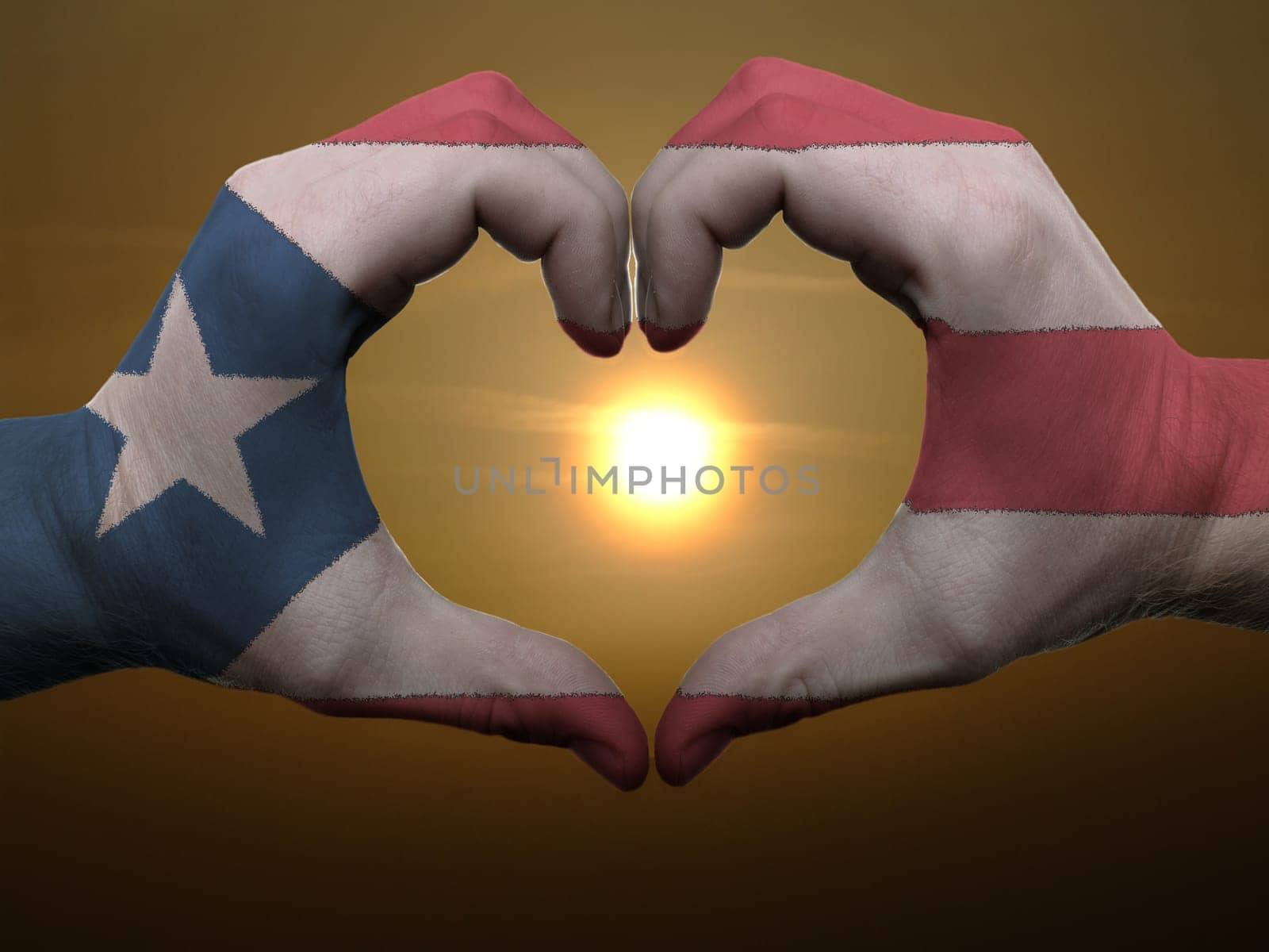 Gesture made by puertorico flag colored hands showing symbol of heart and love during sunrise