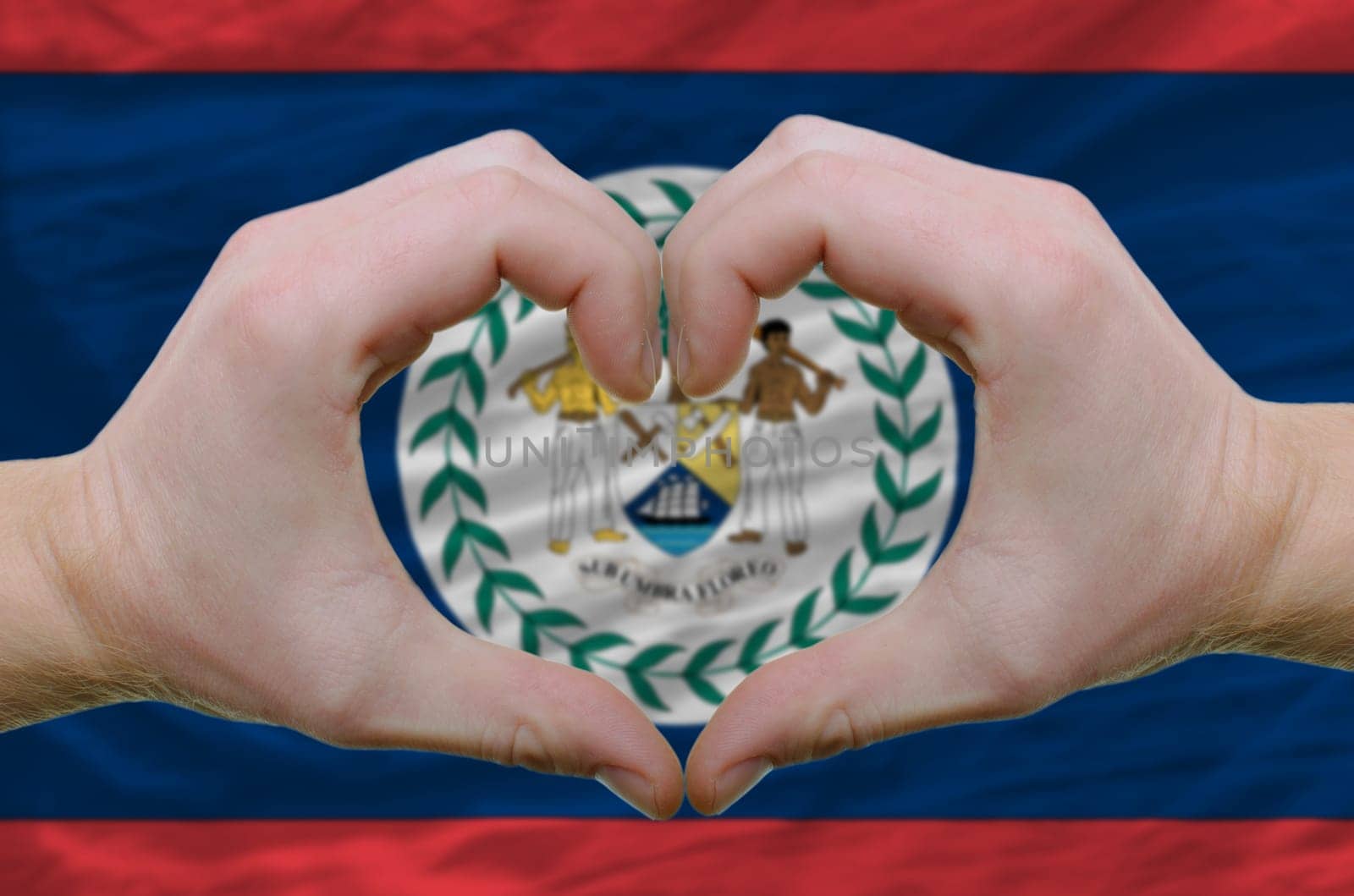Gesture made by hands showing symbol of heart and love over belize flag
