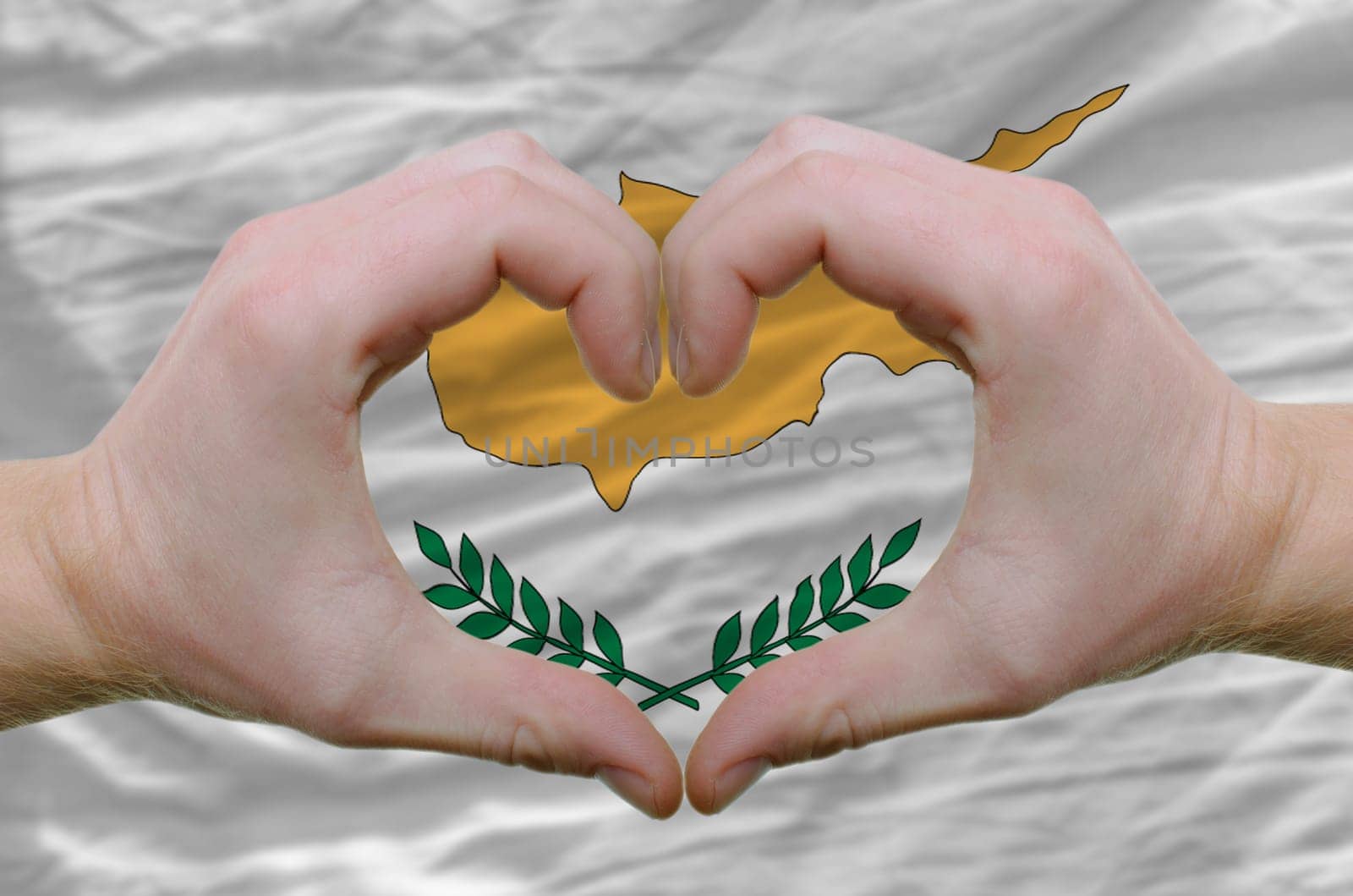Gesture made by hands showing symbol of heart and love over cyprus flag