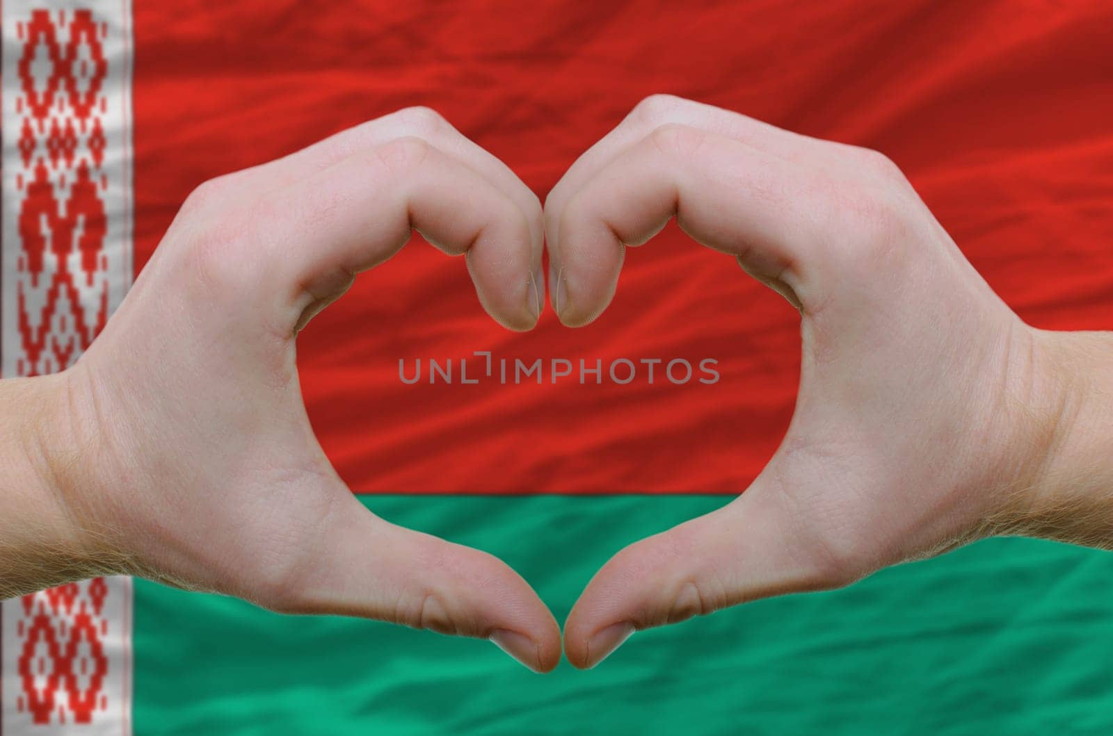 Gesture made by hands showing symbol of heart and love over belarus flag
