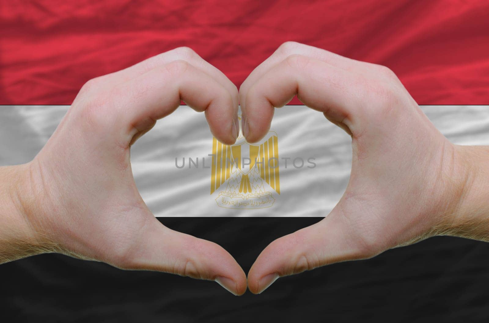 Gesture made by hands showing symbol of heart and love over egypt flag