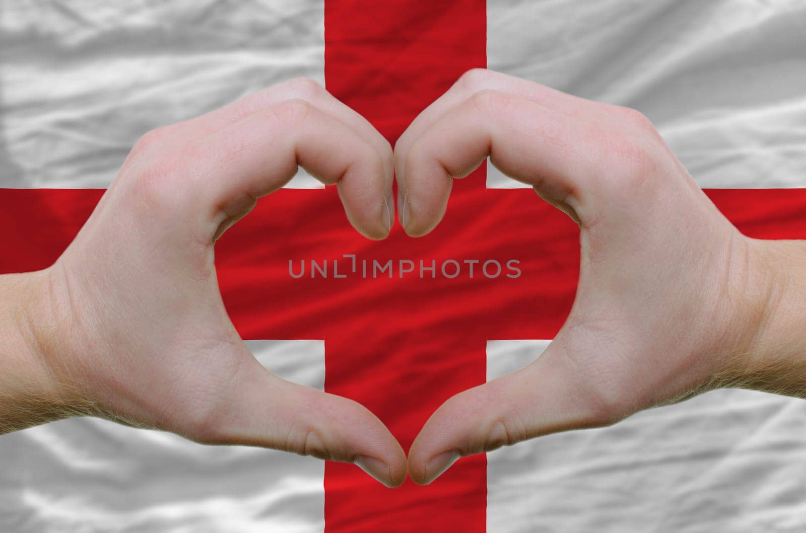 Gesture made by hands showing symbol of heart and love over englandr flag