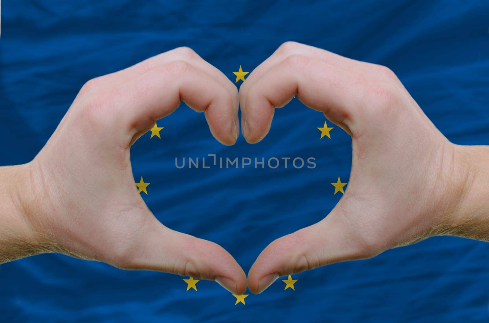 Gesture made by hands showing symbol of heart and love over european union flag