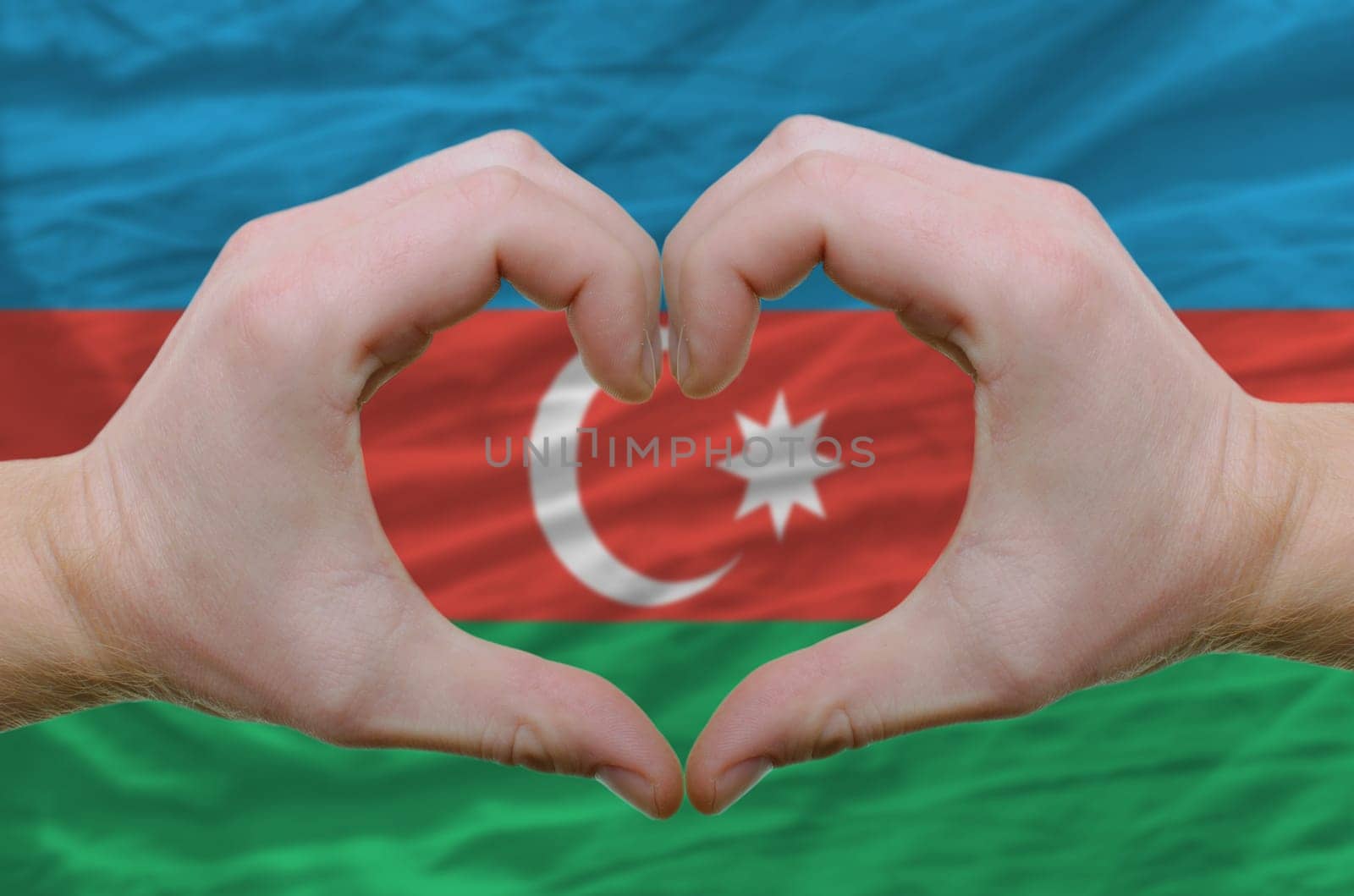 Gesture made by hands showing symbol of heart and love over azerbaijan flag