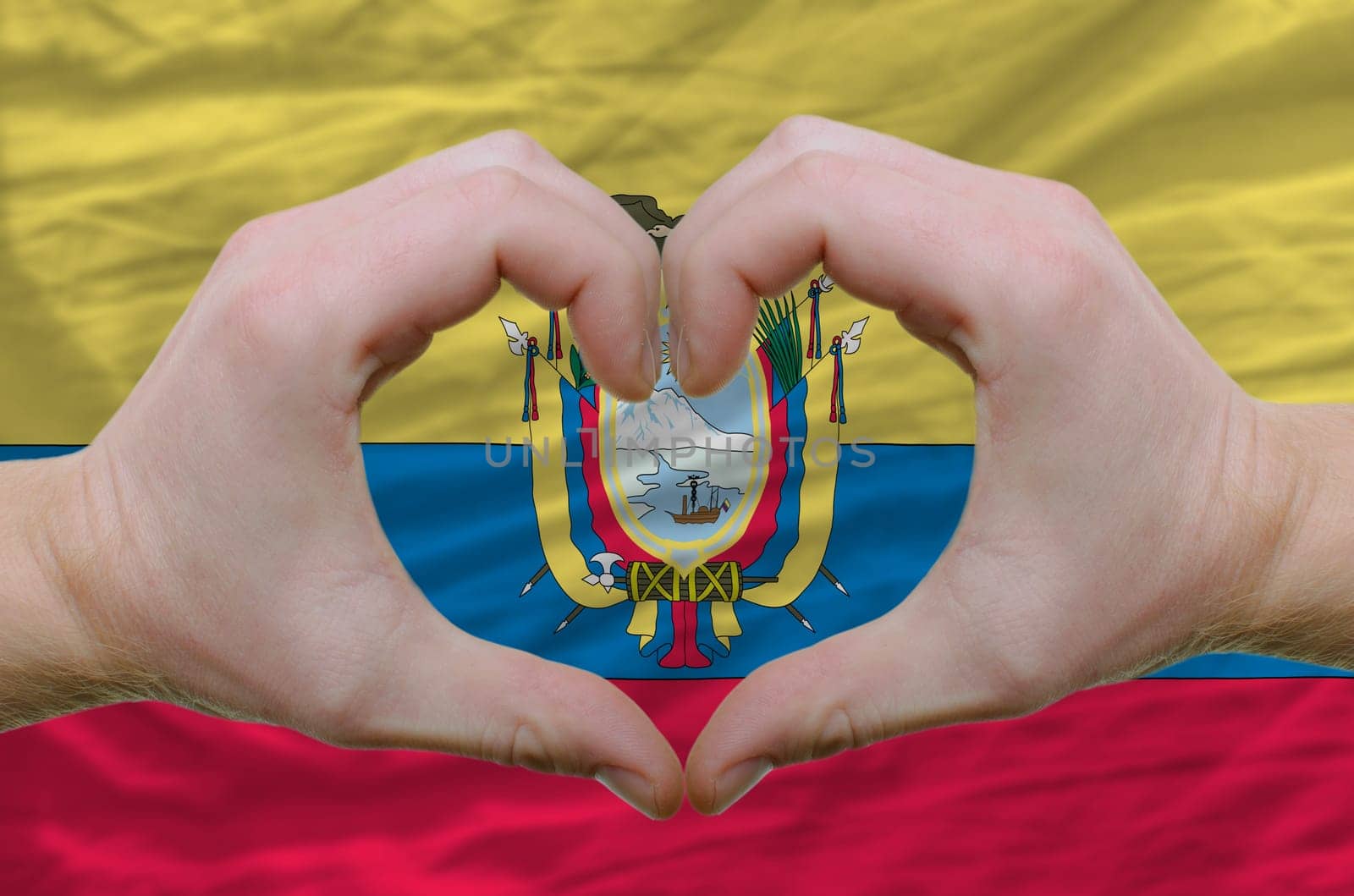 Gesture made by hands showing symbol of heart and love over ecuador flag