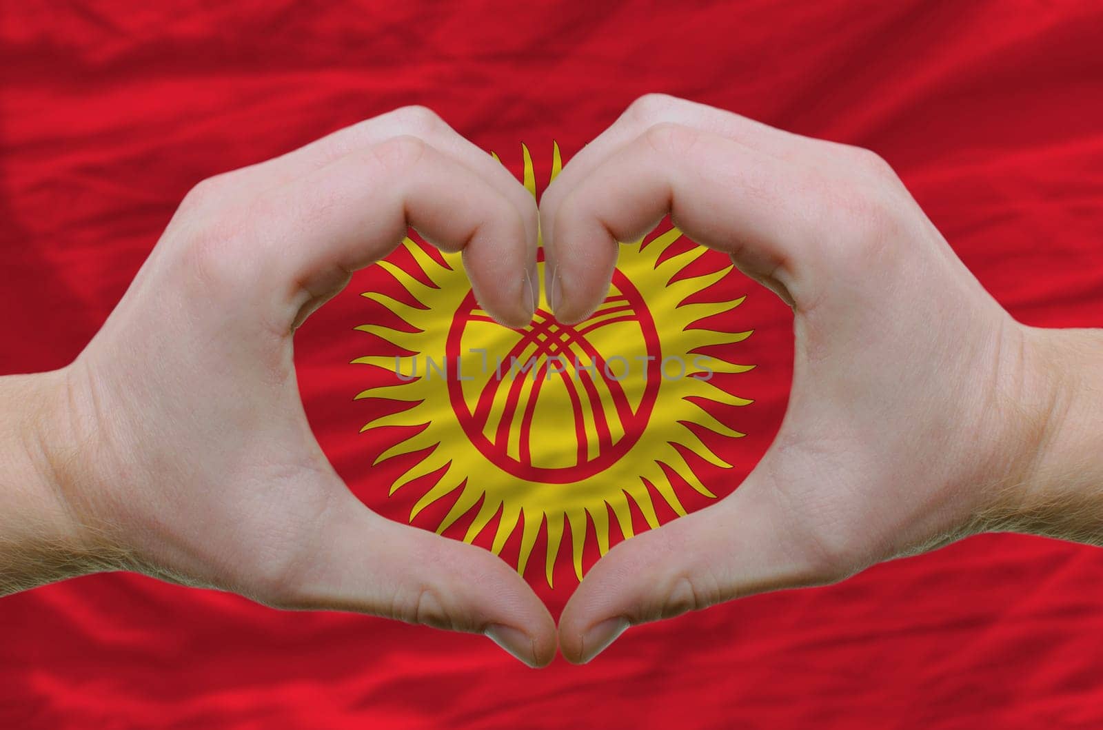 Gesture made by hands showing symbol of heart and love over kyrghyzstan flag