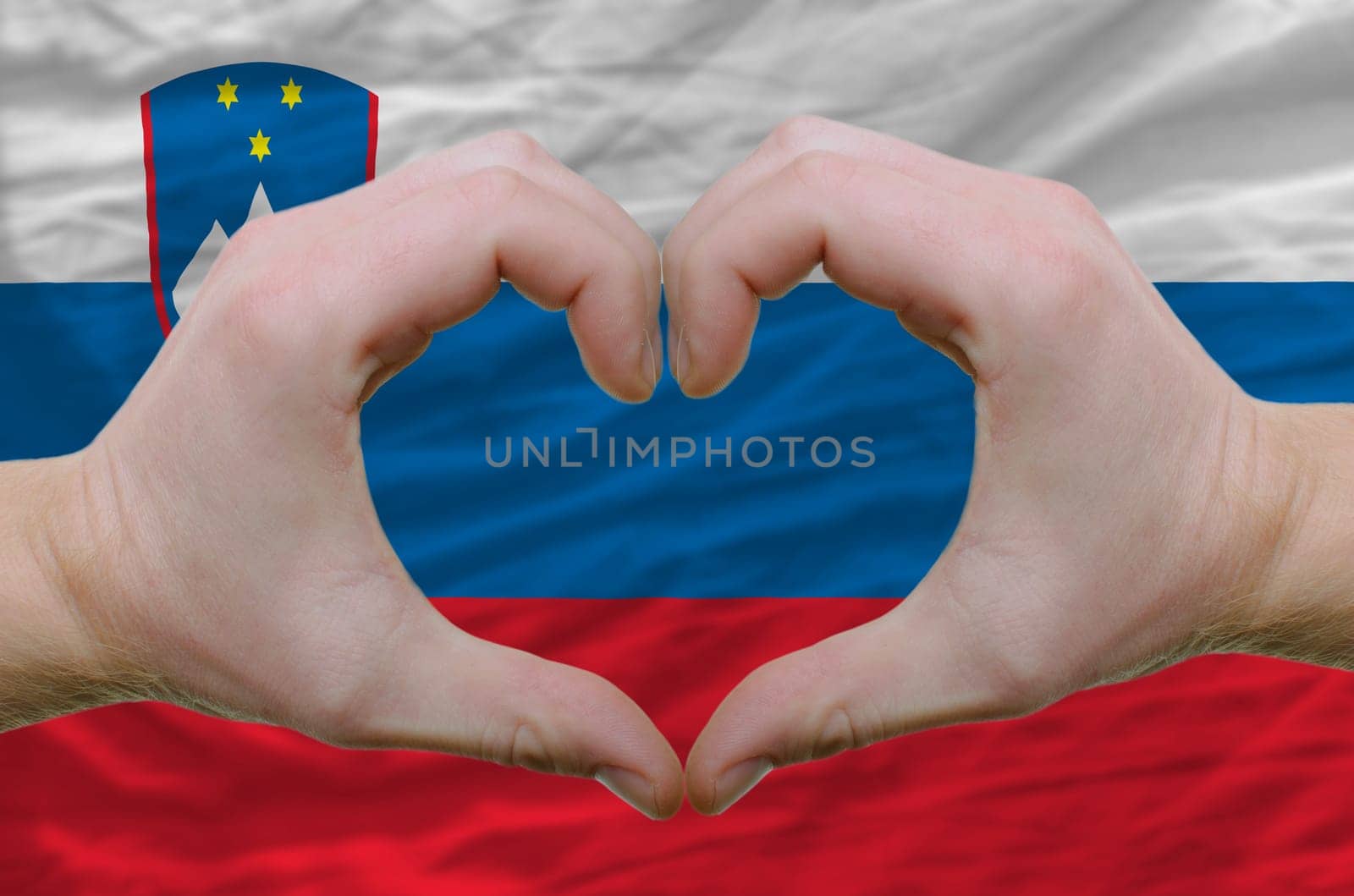 Gesture made by hands showing symbol of heart and love over slovenia flag