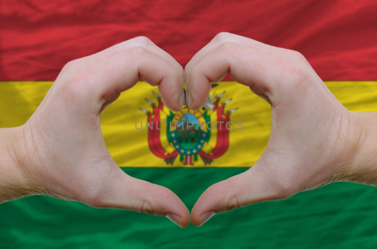 Gesture made by hands showing symbol of heart and love over bolivia flag