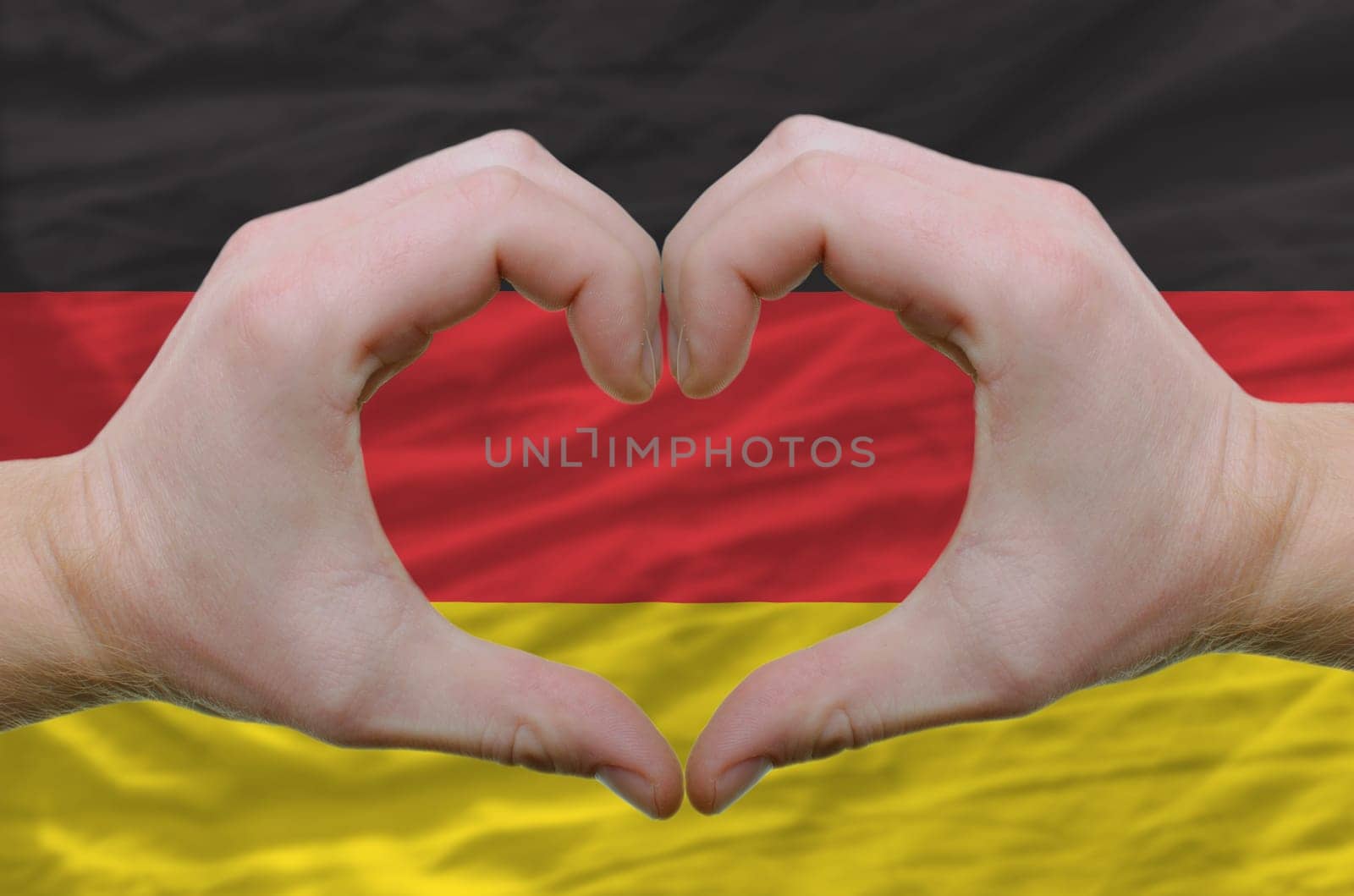 Gesture made by hands showing symbol of heart and love over germany flag