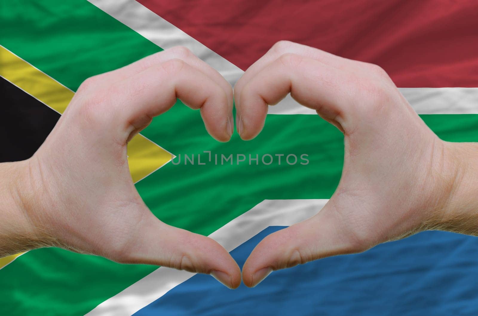 Gesture made by hands showing symbol of heart and love over soth african flag