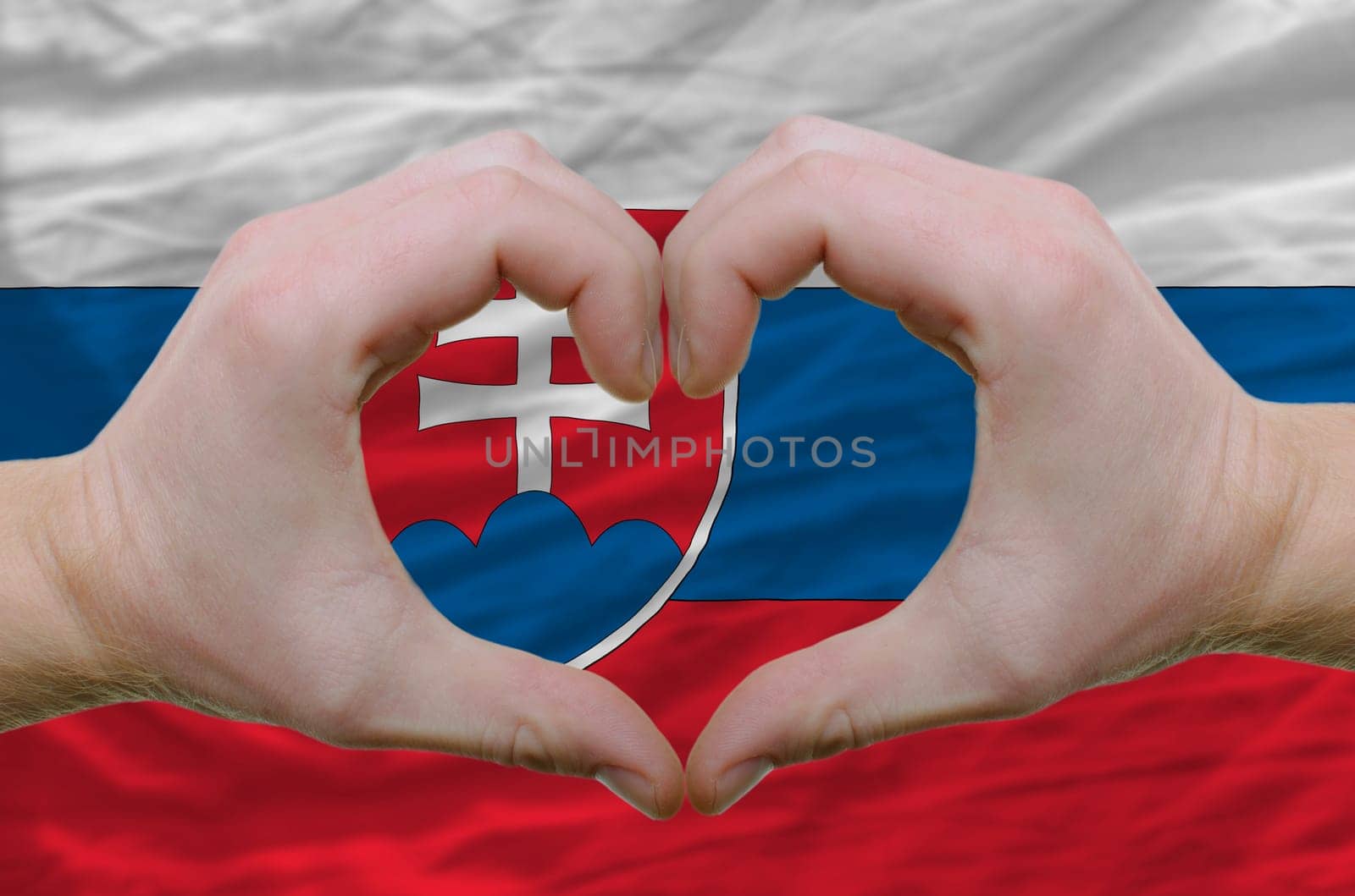 Gesture made by hands showing symbol of heart and love over slovakia flag