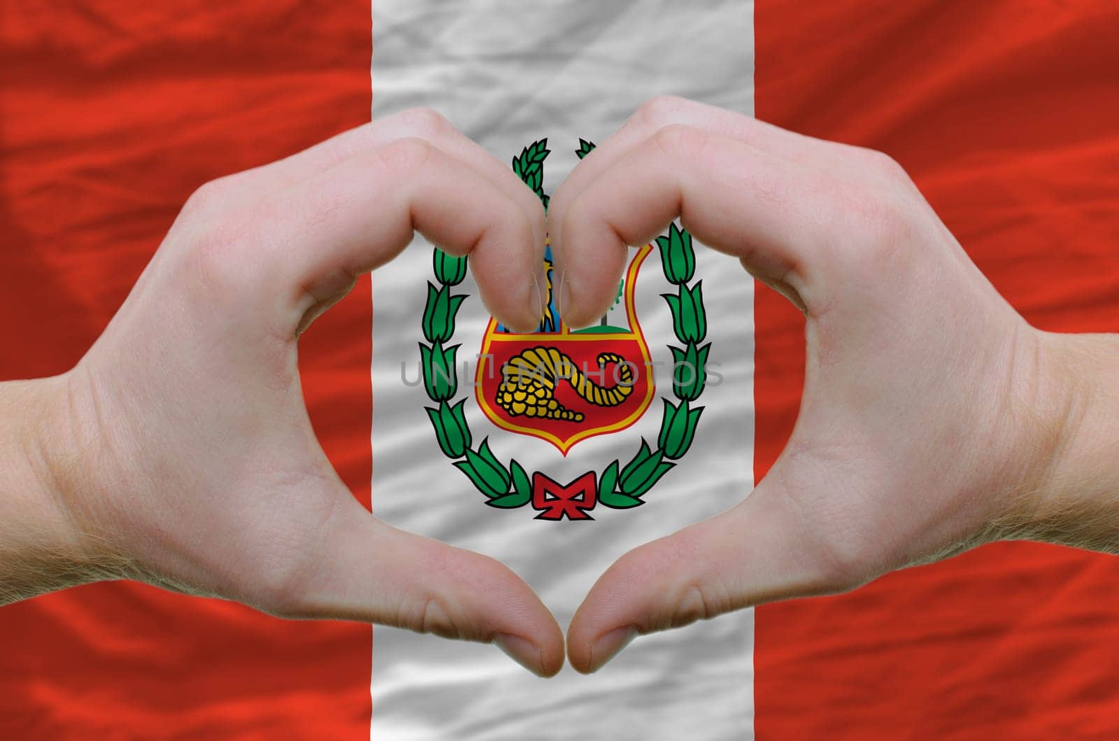 Gesture made by hands showing symbol of heart and love over peru flag