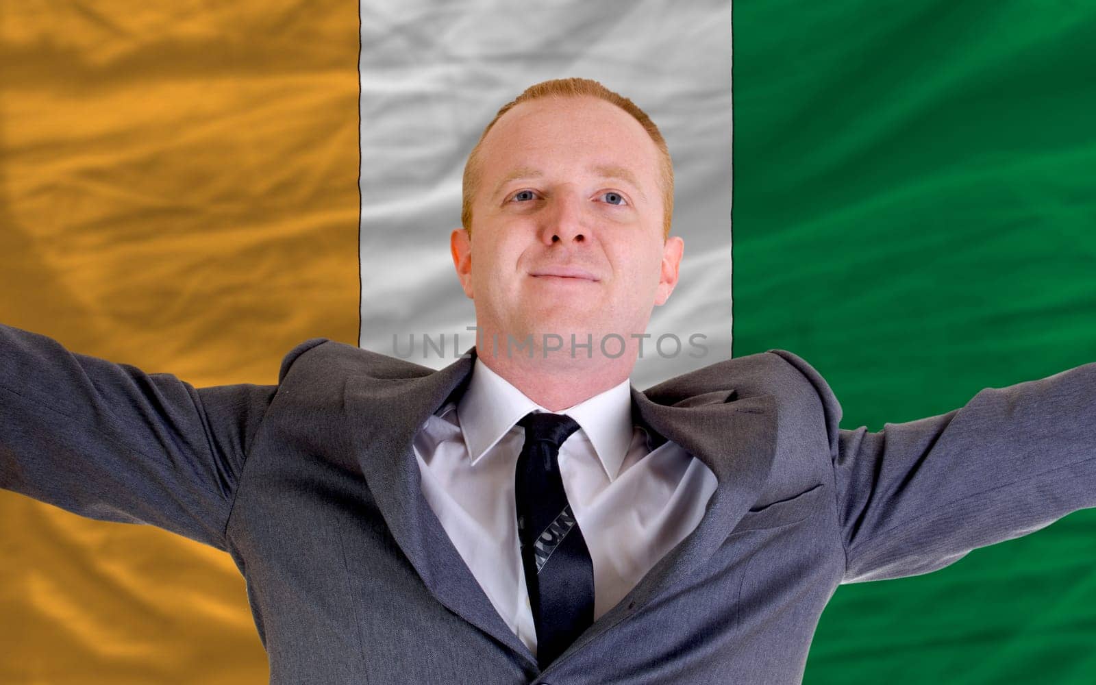 joyful investor spreading arms after good business investment in cote&#039 d ivore, in front of flag