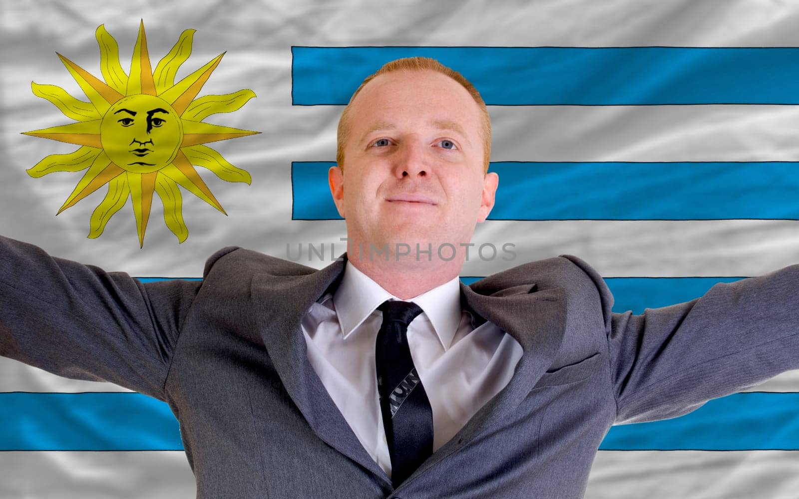 joyful investor spreading arms after good business investment in uruguay, in front of flag