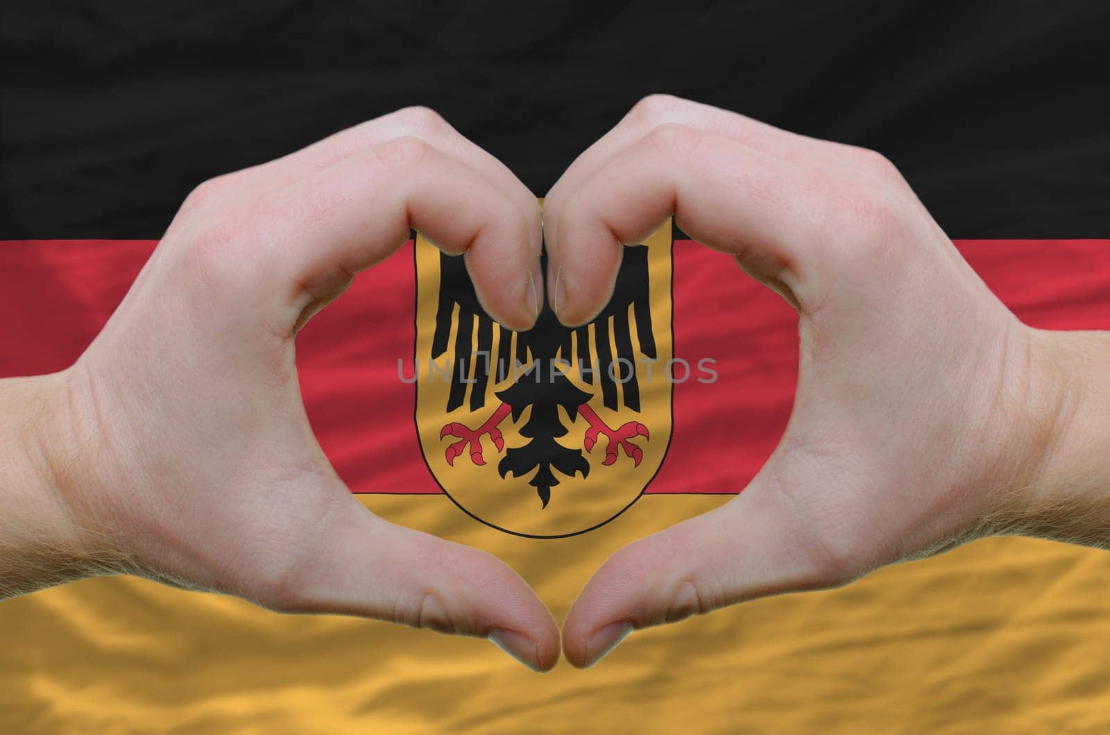 Gesture made by hands showing symbol of heart and love over germany flag