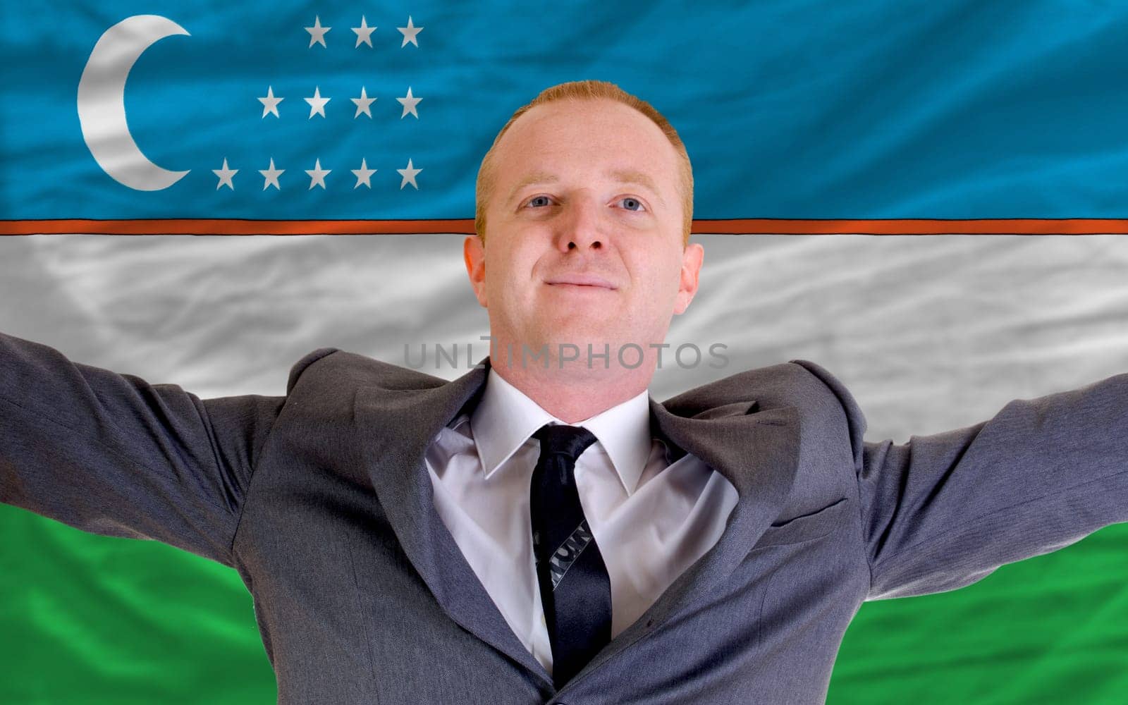 joyful investor spreading arms after good business investment in uzbekistan, in front of flag
